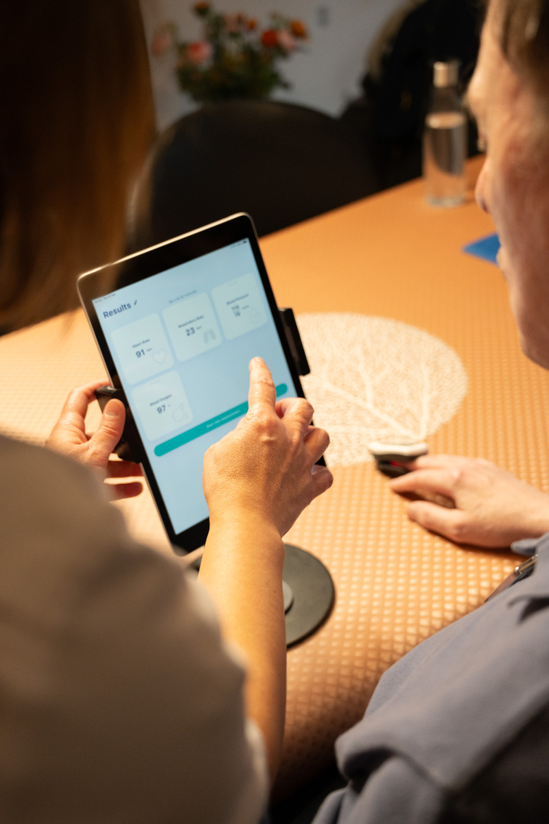 Verpleegkundige bekijkt samen met de patiënt de parameters op de tablet