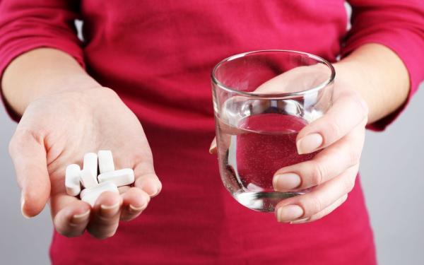 Medicatie in de hand met glas water
