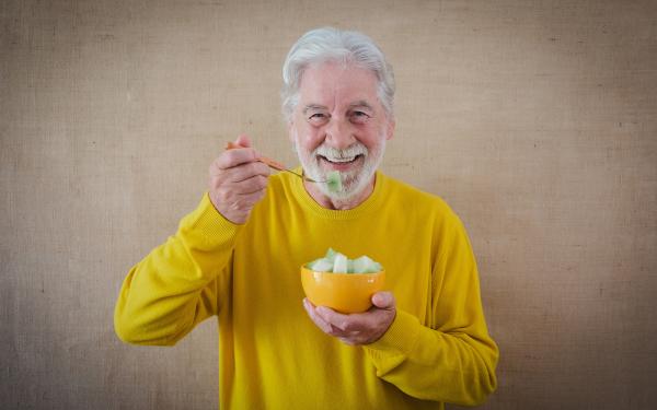 Foto oudere man met stoma die van zijn voeding geniet
