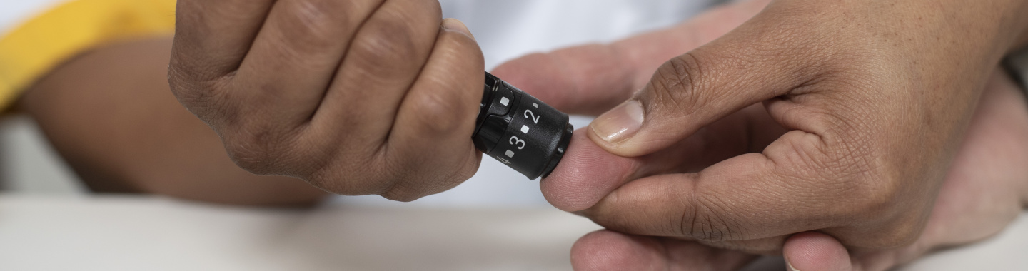 Foto verpleegkundige meet bloedsuiker bij patiënt door een prik in de vinger
