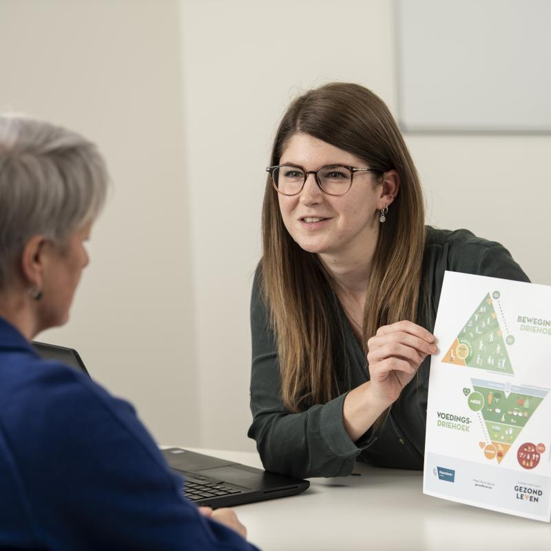 Foto diabeteseducator toont voedingsdriehoek aan patiënt met diabetes type 2