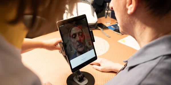 Patiënt laat zijn gezondheidsparameters meten met behulp van een gezichtscan via een tablet
