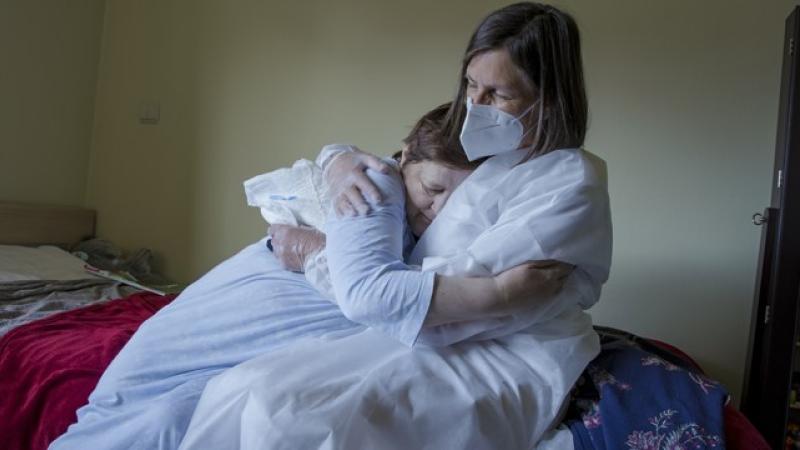 Verpleegkundige met mondmasker omarmt patiënt