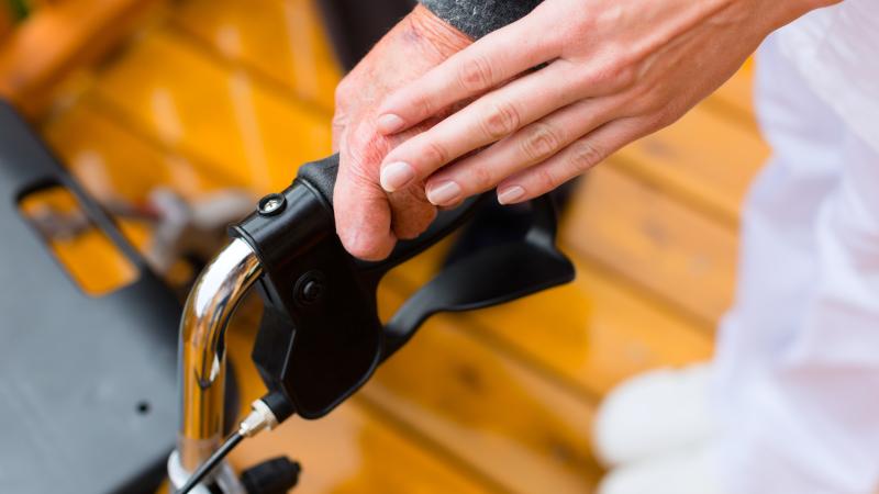 Persoon helpt iemand met looprekje zijn evenwicht te bewaren